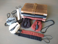 All Riggbee products. Leather journal covers, pacifier clip bracelets, and necklace satchels. Gray background. 