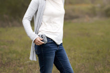 Load image into Gallery viewer, Satchel in Dusk color on woman&#39;s hip belt clip, and she is opening it using the hanging bead. 